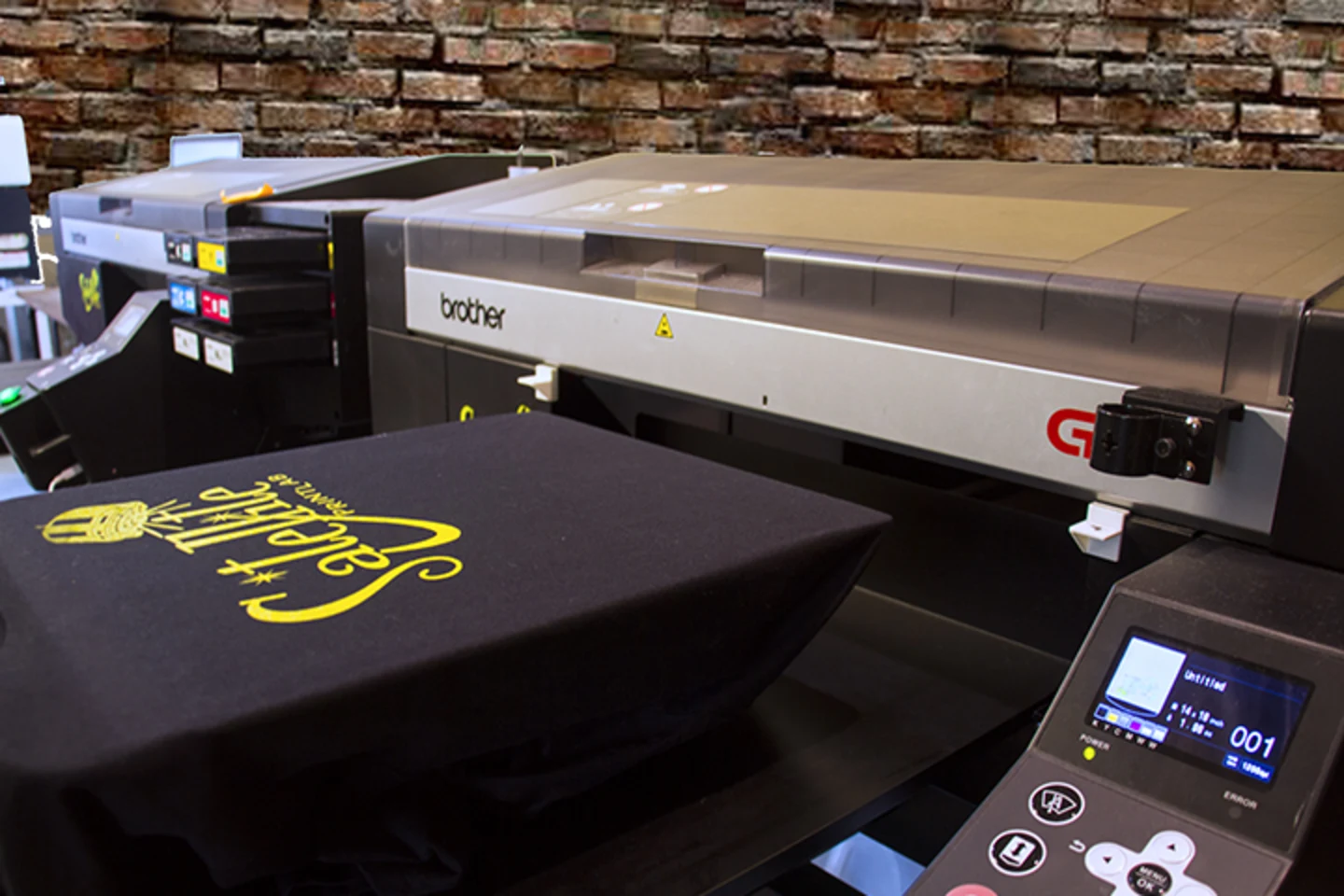Direct to garment printer producing a custom black T-shirt at Satellite PrintLab